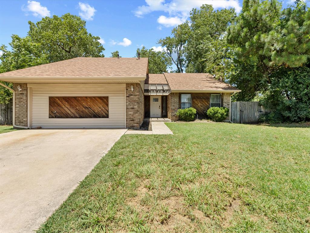 Ranch-style home featuring brick siding, driveway, roof with shingles, and a garage