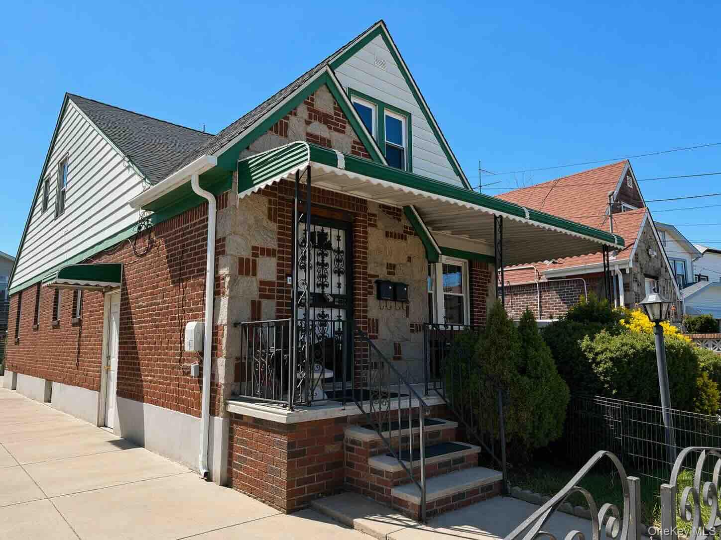 Bungalow with a gate, a fenced front yard, covered porch, brick siding, and stone siding