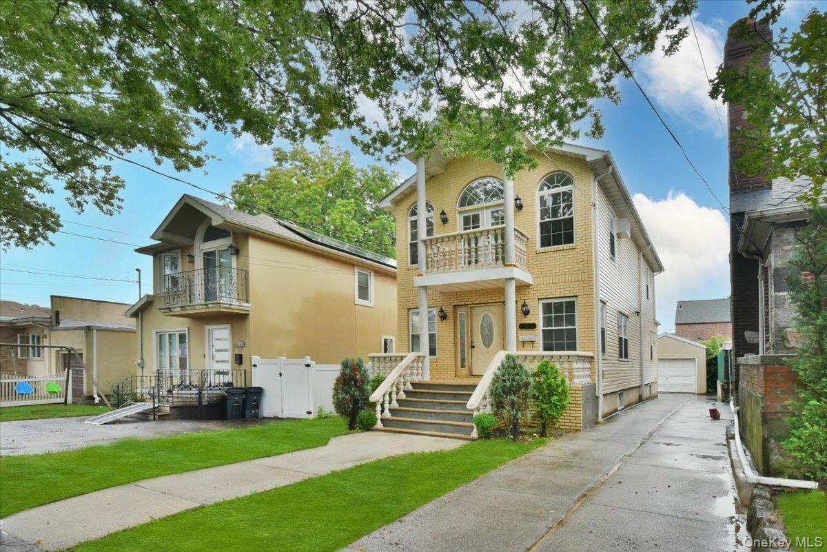 View of front of home featuring a balcony, a detached garage, and an outdoor structure