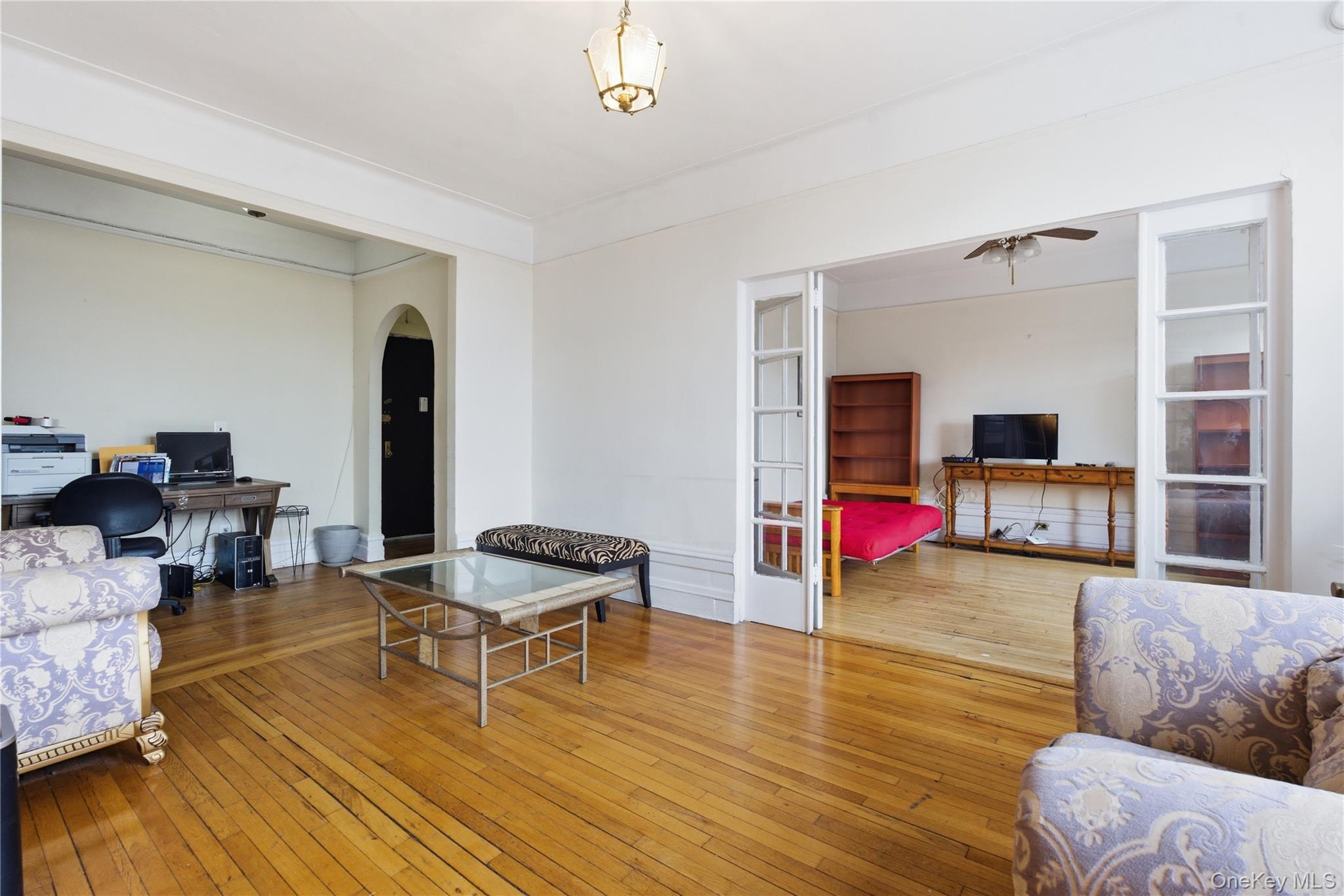 Living area with hardwood / wood-style flooring, arched walkways, an office area, and french doors