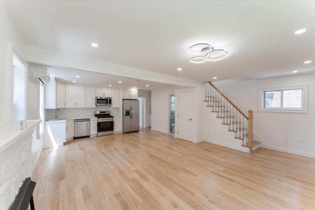 Unfurnished living room with stairs, light wood finished floors, recessed lighting, and an AC wall unit
