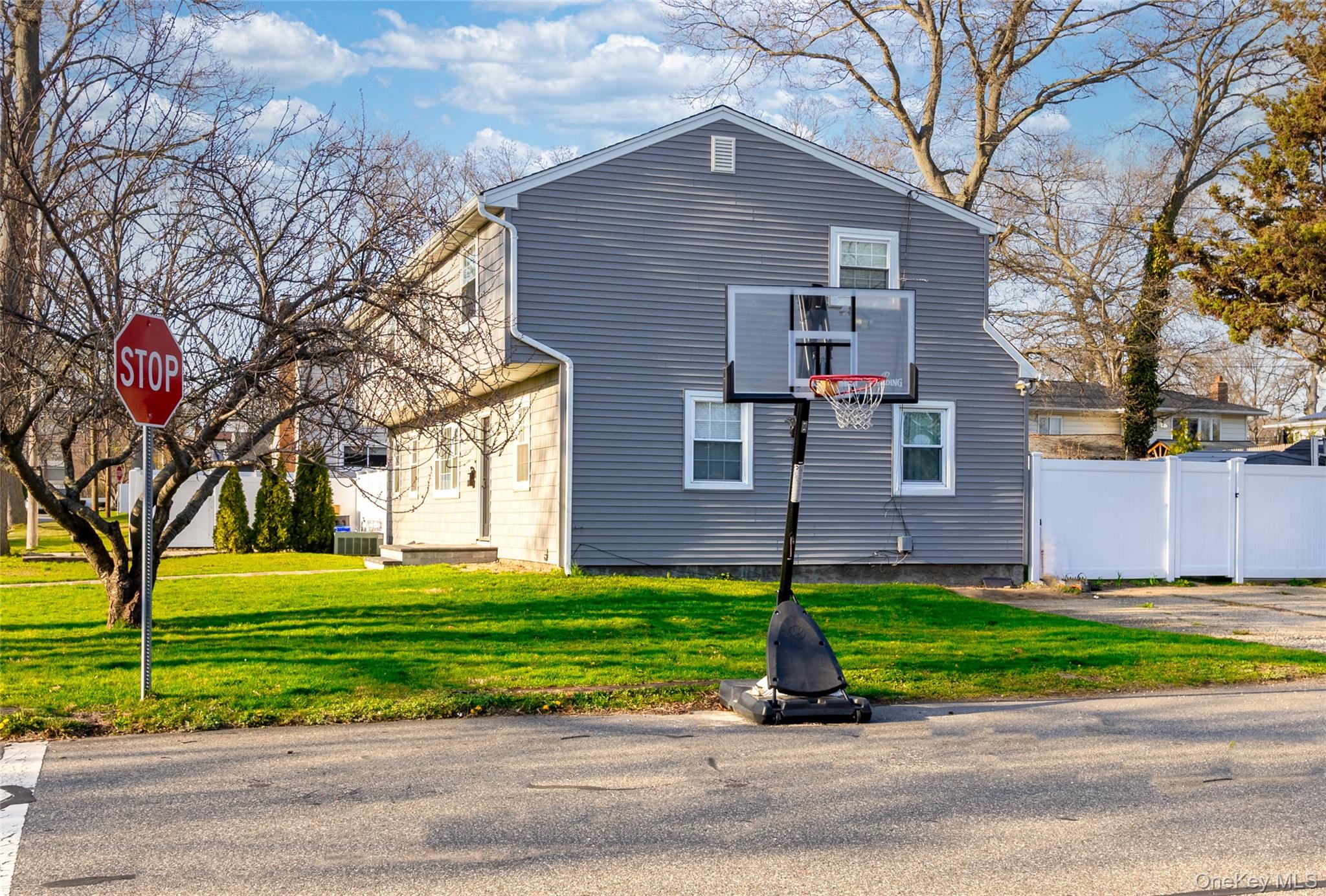 The property features gray siding, white trim windows, and a well-maintained lawn
