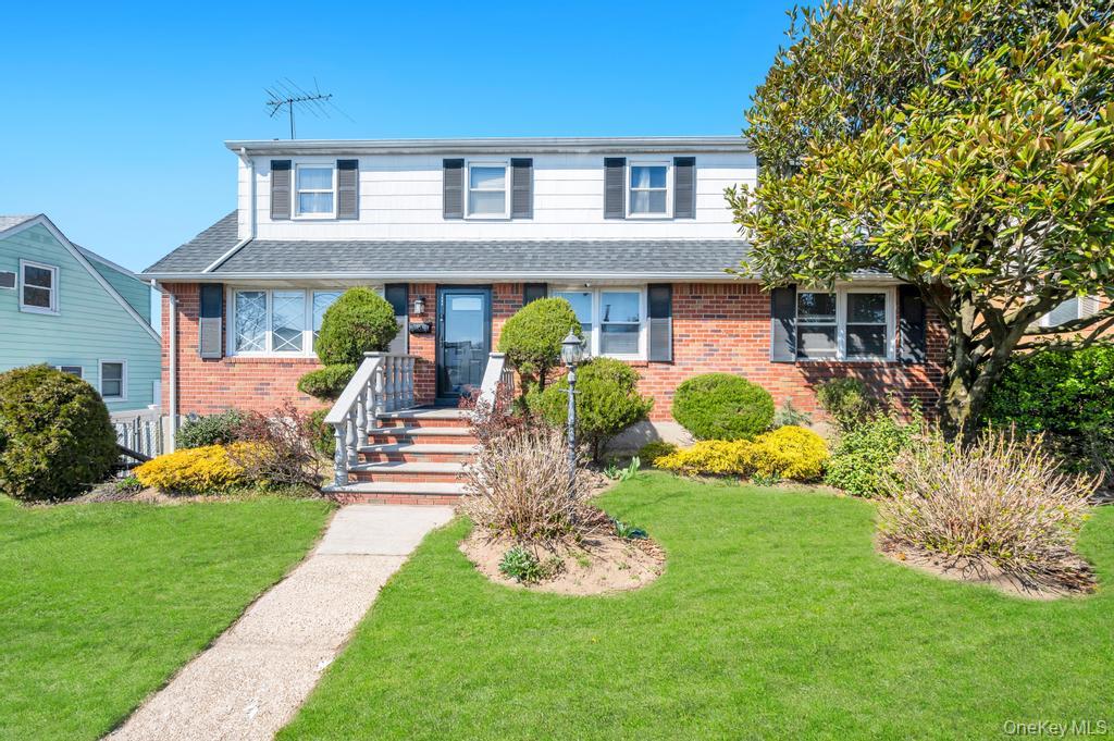 Traditional home featuring a front yard, brick siding, and a shingled roof