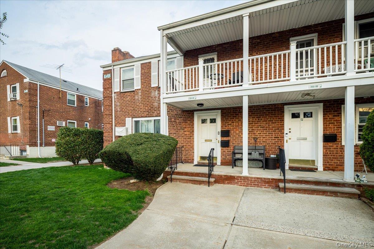 Brick exterior featuring white double doors, a second-story balcony with white railings, and a concrete pathway