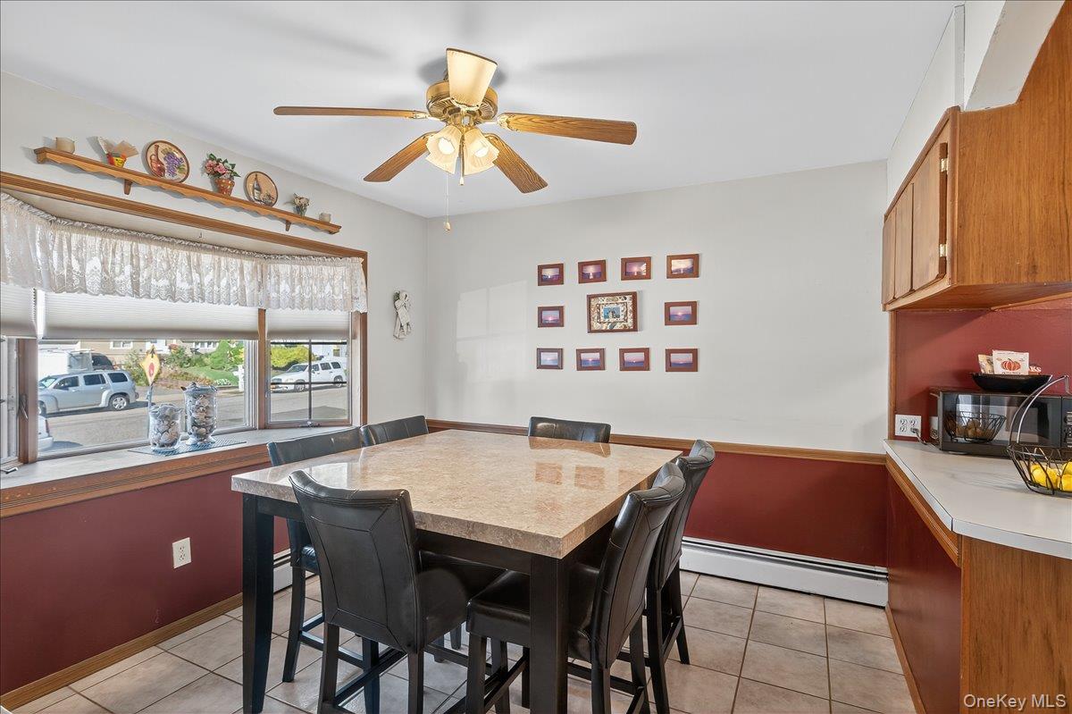 Dining area with light tile patterned floors, a baseboard radiator, and ceiling fan