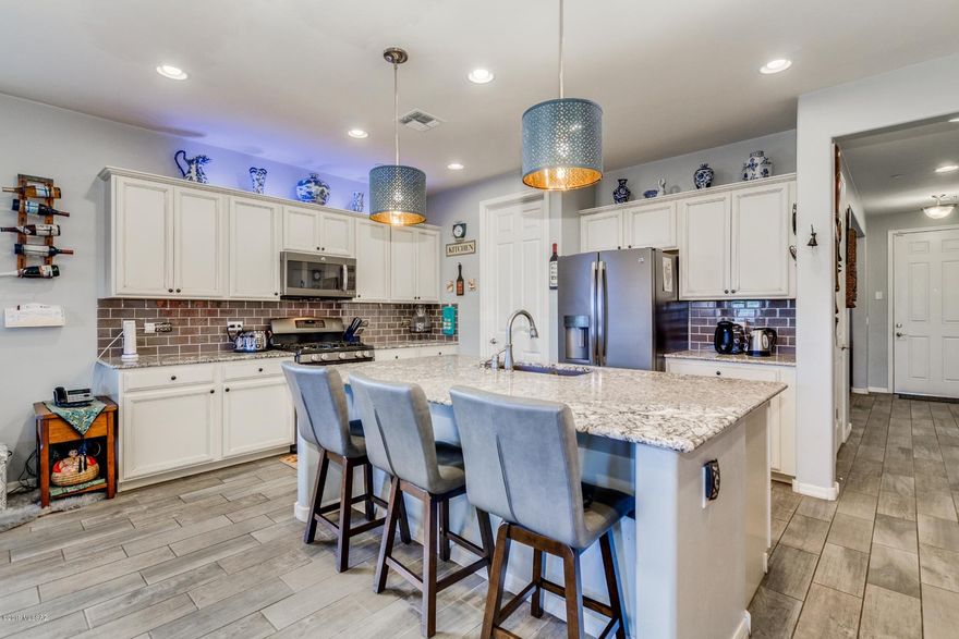 Gorgeous 5 bd 3 bath home with 3,000+ sqft of living space located in the highly sought after Rancho Sahuarita. The light and airy kitchen boasts white crisp cabinetry. Beautiful, expansive kitchen island with bar seating, granite counters, SS appliances, gas range, stylish pendant lights, and eye catching brick-look backsplash. Flowing wood-look tile flooring in all the main living areas, plush carpets in nicely sized bedrooms, flex space, sitting area or office space. Large laundry room, recessed lighting throughout. Upstairs enjoy a large loft space/media space, and the peaceful master retreat equipped with immaculate ensuite and lofty walk-in closet. The well-designed backyard hosts low care desert landscaping and synthetic grass. Come see this beauty today!