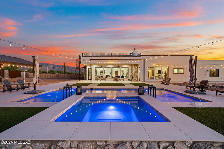 Introducing a rare opportunity in Tucson's luxury landscape, offering both newer construction and acreage, this masterpiece nestled on 4.91 acres of serene and secluded land is for those seeking unparalleled privacy and tranquility. Newly built in 2022, this custom-built Santa Barbara Ranch inspired home boasts a sophisticated charm and a myriad of luxurious features. The home can also be purchased with the 3.2 acre lot next door for the option to own a sprawling 8.1 acre compound. 

This architectural marvel showcases an impeccable floor plan with a split layout encompassing 5 bedrooms, 5 full bathrooms, a den, and an office. The property includes an attached Casita/Guest Quarters with its own entrance and full bathroom, making it ideal for multi-generational living. Every bedroom has its own ensuite bathroom. One of the most functional features of the property is the absence of interior steps ensuring seamless movement throughout the home for years to come. The extended length 5-car garage (3 car + 2 car) with electric vehicle charging hookups is suitable for the most discerning car enthusiast.
Commanding breathtaking views of the majestic Catalina Mountains, this property strategically incorporated large picture windows in every room to maximize the picturesque views from every angle. The 14-foot ceilings in the expansive great room showcase both walnut accents and a custom ceiling design that exude a sense of opulence and sophistication. Other interior features include walnut wood doors throughout, ceramic wood plank tile throughout (no carpet), and a custom stone gas and wood burning fireplace in the great room. Exterior touches include an expansive paver driveway and an impeccably smooth stucco finish that are a testament to the quality of construction of this home.

The heart of this residence is the chef's kitchen, equipped with top-of-the-line appliances such as a separate Electrolux refrigerator and freezer, a six-burner gas range with a double oven, quartz countertops, 2 sinks, dual walnut kitchen islands, and a peninsula for effortless entertaining. A pre-installed wine cellar adds an extra touch of elegance to the culinary space.

The lavish primary suite features outdoor access to the backyard, a spa-like bathroom with a soaking tub, a custom shower, and separate vanities with walnut cabinetry. The primary closet also has its own waster and dryer hookup for ultimate convenience. 

Step outside to discover a resort-style backyard, complete with a heated pool and spa, spill-over waterfall and laminar water features, and artificial turf surrounding the pool. The expansive covered patio is complete with sleek pavers, a gas & wood burning fireplace, and a TV for entertaining. A separate sunken patio area with a wood-burning fire pit offers the perfect setting for outdoor gatherings and relaxation. Additional backyard features include a large functional outdoor Ramada with electrical and water pre-installed and a spiral staircase leading to a roof-top observation deck with 360° views. The fully enclosed custom fence surrounds the backyard with stone pillars is optimal for pets and provides security and privacy.

This property is perfect for any hobby or travel enthusiasts with 50-amp RV hookups and dump station, as well as 2 access gates making pulling through with your truck or RV a breeze. With plenty of room and acreage, the possibilities are truly endless on this expansive and versatile land.

Experience the epitome of luxury living with this exceptional property that seamlessly blends modern amenities with natural beauty. Don't miss the chance to make this exquisite retreat your own.
