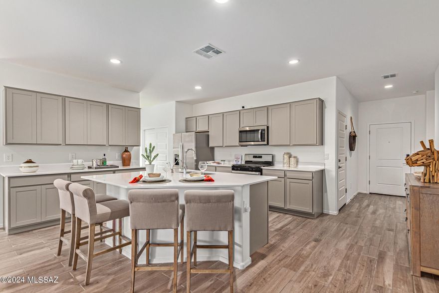 Welcome to the Kingston, a stunning 2051 sq. ft. single-story home now available in the newest phase of Saguaro Bloom, Block 7C - Agave. This popular floor plan features 4 bedrooms and 2 bathrooms, thoughtfully designed for modern living. At the entry, you'll find two bedrooms and a hall bath, with an additional bedroom conveniently located off the kitchen. The HUGE primary suite is situated at the back for ultimate privacy.

The open great room design boasts an oversized, angled island and an extra wall of cabinets and counter space, perfect for entertaining and everyday living. We've enhanced this standout plan by replacing two windows and a single French door off the great room with an oversized slider, seamlessly connecting the indoor space to the covered patio. SRAYFOAM INSULATION!