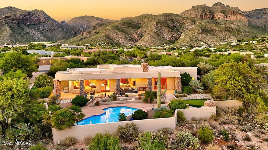 Located in prestigious guard-gated Pima Canyon Estates, this stunning Southwest Contemporary home captures both incredible city lights and dramatic mountain views. Enter through a gated courtyard with a soothing waterfall, and step inside to be greeted by a large picture window framing a majestic saguaro, lush desert landscape, and sweeping vistas. The dining room boasts Catalina Mountain views and a coffered ceiling, while the living room is anchored by a rustic stacked stone fireplace. The gourmet kitchen features a large island, Alder cabinets, quartz counters, KitchenAid and Liebherr appliances, an oversized walk-in pantry and flows seamlessly into the casual dining area with built-in desk and additional cabinetry. The primary suite offers a newly remodeled spa-like bath with two generous walk-in closets, a luxurious soaking tub with private views, and a tiled separate shower. Outdoor living shines with a long covered patio, newly plastered pool, stacked stone fireplace, putting green, and breathtaking views in every direction. Additional highlights include a 3-car garage with coated flooring and extra storage, water softener, central vac, new washer & dryer, and sump pump. Exquisitely maintained yet inviting and comfortable, this home is a true desert retreat.