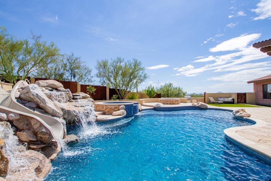 Exquisite, MILLION DOLLAR VIEWS from this uniquely PRIVATE HOME .Resort style backyard! Sparkling pool, waterfall slide, Spa, built-in BBQ, fire pit, travertine patio, sports court, & covered patio. High-end upgrades throughout w/beautiful tiled floors, walls of windows , plenty of natural light, upgraded lighting/ceiling fans,layered stone accents. Kitchen boasts granite counters ,island top, s/s appliances, walk-in pantry leading to formal dining area.The master suite with open loft featuring built-in bookshelves, spectacular natural light , 180 views, through double French doors, to a semi-circular outdoor balcony , on suite bath ,designer tub, stone-tiled shower , a separate commode, large walk-in closet, Large laundry room w/storage cabinets & sink can be used for a hobby room. this incredible staycation home is a one of a kind desert gem! See It! Love It! Live It!