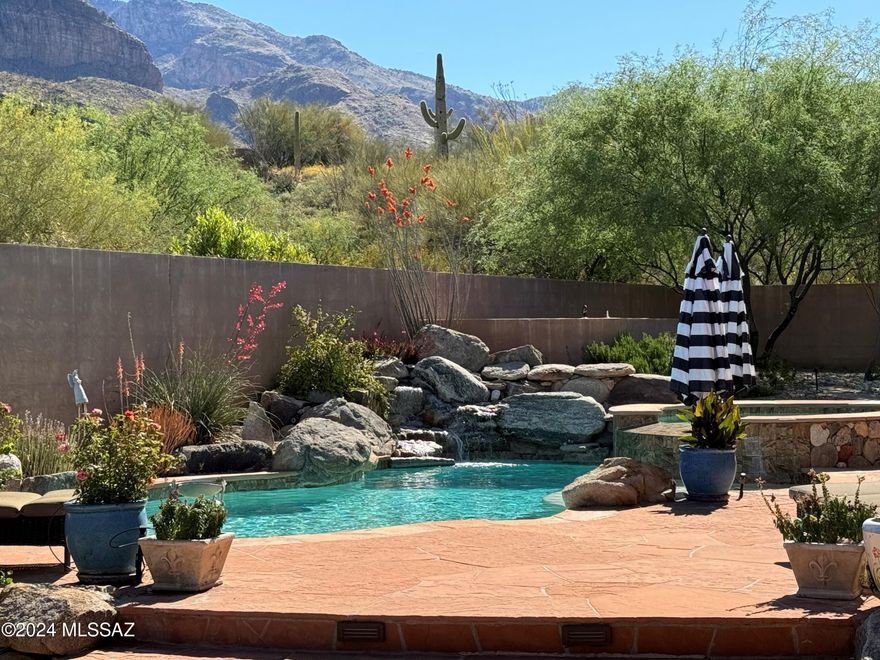 Experience the highly desired Arizona lifestyle in this beautiful 3,740 SF custom home located within the prestigious guard-gated community of Pima Canyon Estates.  Step inside to an expansive great room with hardwood floors, natural gas fireplace, open kitchen and a wall of glass framing the luxurious backyard and breathtaking views of the Catalina Mountains. This luxury home boasts a private entertaining oasis with pool, spa, waterfall, fire rings, built in BBQ, and both front and rear covered patios. The kitchen features a Viking range with dual Viking ovens and two dishwashers. This lovely home was thoughtfully constructed with energy efficient and sound absorbent RASTRA ICF insulated concrete forms. Seller is a licensed real estate agent in Arizona