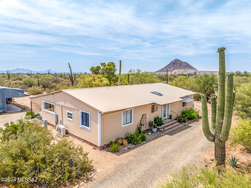 Lovely desert oasis with natural landscaping on 1.67 acres, fully fenced. Great room has large windows overlooking lush yard. Large rear covered porch and patio. 1200 sf metal building with attached enclosure for goats, chickens, etc. plus 2 storage sheds. Two year old metal roof, freshly painted inside and out.