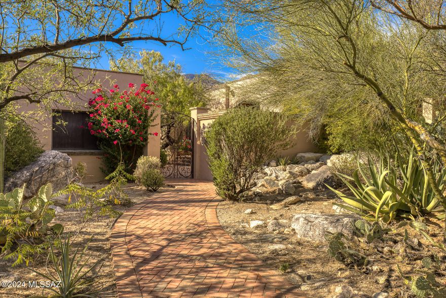 Nestled on a private, 1-acre lot at the top of the Catalina Mountain foothills, this exceptional custom home offers unparalleled desert beauty and up-close mountain views. Located in the prestigious gated community of Canyon View Estates, between Ventana Canyon and Sabino Canyon, this home embodies the best of Tucson's landscapes, lifestyle, & luxury.
Step through a custom entry gate into a serene courtyard shaded by mesquite trees, setting the tone for the bright & inviting interior. The open floor plan is designed to showcase the surrounding beauty with walls of windows, honed flagstone floors, and high-quality finishes throughout. The great room is centered around a striking Cantera fireplace, while the dining area and den offer versatile spaces for living and entertaining The home's deep, covered brick patios wrap around the property, creating a seamless transition to outdoor spaces. Just off the kitchen, an outdoor dining area with a built-in BBQ provides the perfect setting for al fresco meals and gatherings.
The recently remodeled kitchen is a chef's dream, featuring custom cabinetry, Caesarstone and Granite countertops, a Viking six-burner oven and cooktop with a hood vent, and a Sub-Zero refrigerator/freezer. A Bosch dishwasher and microwave add to the modern convenience, while a center island with a wine refrigerator & bar seating complete the space. Adjacent to the kitchen, the dining nook is bathed in natural light & offers stunning views of the desert and mountains. A custom-built buffet provides additional storage and adds a functional yet elegant touch.
The primary suite is a true retreat, featuring a dramatic fireplace, 2 walk-in closets, and breathtaking views. Direct access to a private covered patio, offering a quiet sanctuary to enjoy the natural surroundings. The ensuite bathroom is spa-like in its design, with dual vanities, a large steam shower, and a soaking tub. The second bedroom serves as a luxurious guest suite with a beautifully updated ensuite bathroom, while the third bedroom offers flexible space that can easily function as an office or studio.
The resort-style backyard strikes a perfect balance between natural desert beauty and modern amenities. A Cantera-bordered lap pool is surrounded by native cacti and plants, creating a tranquil setting for relaxation. Multiple private patios and seating areas are ideal for dining, reading, or simply taking in the stunning landscape.
Additional features include a two-car garage with a separate office. With its north-south orientation, the home is bathed in natural light throughout the day.
This property is located just minutes from Sabino Canyon Park, Ventana Canyon Resort, world-class golf courses, fine dining, and shopping, all within the highly regarded District 16 school district. Offering the perfect combination of elegance, functionality, and access to Tucson's most desirable amenities, this home is an exceptional desert retreat.