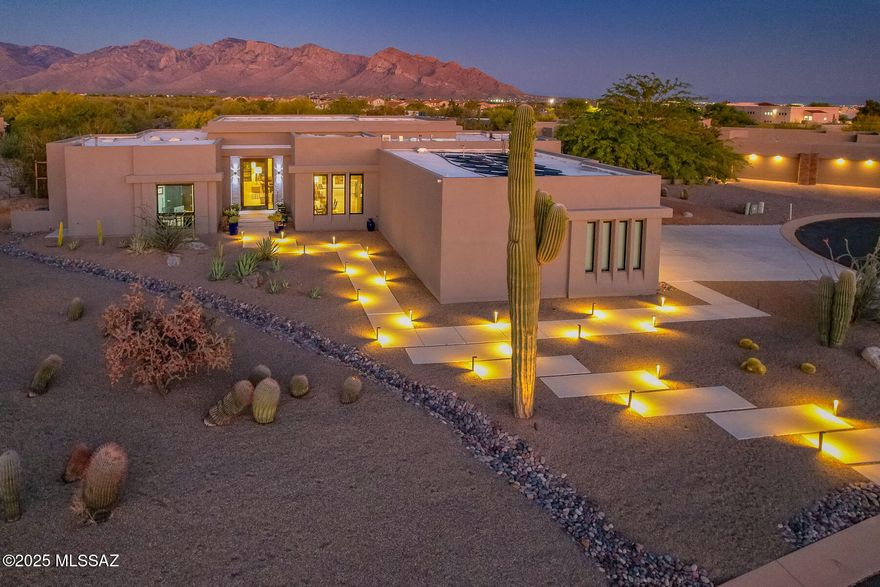 Experience the perfect blend of luxury and modern technology in this small, gated community of Sunset Canyon Estates in Oro Valley. Contemporary, highly upgraded 4BD/4BA (3,355 sf) home on .84 acres showcases a dramatic lighted walkway, 5'x10' pivoting glass entry door, impressive Gathering room and formal Dining room with 450-bottle glass wine display case. Resort-style yard boasts a Travertine stone patio, solar heated pool with raised spa & decorative stone waterfall, stone finished firepit, granite-top grill station, large Botanical Center beyond, plus breathtaking sunsets upon the Catalinas. Richly finished details throughout include 18''x36'' porcelain tiled floors in main living areas, granite counters in kitchen/laundry/baths, walk-in closets in carpeted bedrooms, 1-3/4'' Alder doors plus vogue crystal light fixtures. Expansive Gathering room is highlighted by soaring, recessed ceilings and walls of windows overlooking the yard and mountains. Spectacular gourmet kitchen boasts dual islands with level 4 Alaska White Granite, Charcoal Quartz waterfall edge island with bar seating, counter-to-ceiling glass mosaic tiled backsplash, top-of-the-line appliances, dining nook plus walk-in pantry. Elegant Owner's Suite hosts a luxurious bath featuring dual sink vanity, soaking tub, tiled walk-in shower and large custom closet. Two additional en-suite guest rooms plus 4th bedroom (ideal as an office). Additional amenities include spacious laundry with sink, light filtering skylights, automated window coverings, central vacuum, fire suppression, whole house surge suppressor, smart panel, security features and more! Botanical Center at rear of property offers a meandering, gravel walking path showcasing native plants, olive & bottle brush trees, 250-year-old saguaro cactus plus smaller cacti for your viewing pleasure. Three car garage hosts a sectioned off third bay with 10-foot cabinetry and countertop. Perfect for the most discerning buyer!