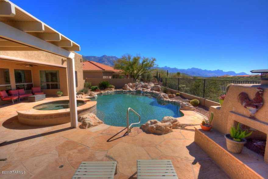 The ultimate in desert living. Modern Santa Fe style home provides relaxed luxury. Resort style back yard features self cleaning solar pool with waterfall and spa. Bordering the open desert space the expansive flagstone patio includes a gas fireplace, built-in gas barbecue and roof cover at the house and extended ramada. Wrap around views of the Catalina mountains from your front living/dining rooms and from the back patio. The southwest theme inside continues with tile floors, Hickory cabinets, wood stained molding & doors and faux painted walls in warm desert colors. Open family room has party wet bar and built-in cabinet for TV, shelves and Energy Efficient gas fireplace. The bright kitchen features all stainless steel appliances, gas cooking and granite counters with under mount sink. Throughout the home, custom ceiling fans, lighting and window treatments.
High ceilings and large picture windows front and back with views of mountains and desert.
Split bedroom plan with large master suite.  Bay window in master bedroom plus luxury bath with deep soaking tub, his/hers sink vanities & his/hers walk-in closets.
2 guest bedrooms share a shower bath.  1/2 powder bath is near the family room. 
The large Saguaro in the front yard defines this Southwest home.
Citrus trees include: Mexican lime, Meyer lemon, Navel orange, Cutie   orange, Valencia orange
Front security screen door.
Roll down solar screens at patio.
3 car garage. 
Stucco fence walls with open rail at the back border.