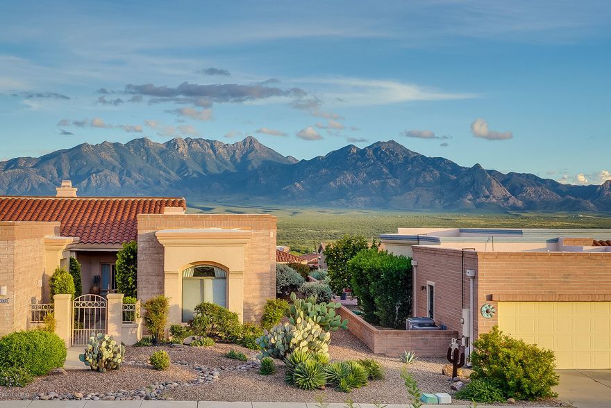 Brick and stucco displays a contemporary design as you enter through an attractive four pillared canopy walkway.  You'll love the angled architecture that guides your way into a broad great room where high vaulted ceilings deliver an open airy feeling.  You will immediately notice the glass sliding doors combined with corner windows to paint picturesque views of the Santa Rita mountains.  The expansive kitchen is wrapped in rich mid-tone cabinetry and its unique shape in conducive to multiple helpers when needed.   The adjacent eat-in nook is a convenient place for light meals.  Off the back master bedroom suite, step through pocket doors leading to a large office area with built in cabinetry.   The split arrangement for the guest ensuite is the perfect arrangement for visitors.  Relax and enjoy beautiful views from your extended brick patio with swaying palm trees and a backdrop of majestic mountain vistas!