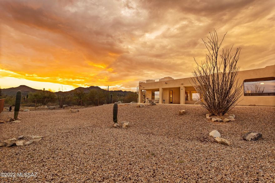 Incredible custom home w/pool on 5 acres (no HOA & owned solar) nestled in the Tortolita foothills offers terrific multi-gen living w/space & privacy for all! Drive through custom gated entrance past dramatic rock formations to this private property that boasts unobstructed panoramic views. Split bedroom plan with TWO master suites, each w/ensuite bath & private patio access + 2 additional BRs, a third full bath, powder room & huge bonus room (home theater, game room, or home school?)  Gather in the great room w/gas-log FP open to chef's kitchen w/custom hickory cabinets, SS appliances, walk-in pantry, granite slab tops + a span of lit display cabinetry below curved breakfast bar. Generous dining nook + adjacent formal dining. Primary master suite occupies one wing w/seating area, walk-in shower w/multiple heads, soaker tub & custom cabinets. Guest wing offers 2nd master w/lg walk-in shower + 2 additional bedrooms, all with beautiful mountain views. Oversized 4-car garage (4th stall walled off w/HVAC for shop or studio) leads into large laundry/mud room next to kitchen. From the covered south-facing patio, you'll marvel at Catalina Mt sunrises and Tucson Mt sunsets. Enjoy blazing sunsets or star-studded night skies from viewing deck with spiral staircase. Imagine the possibilities in your own private paradise! Plenty of room to expand for the equestrian lifestyle, a guest home, or RV garage.