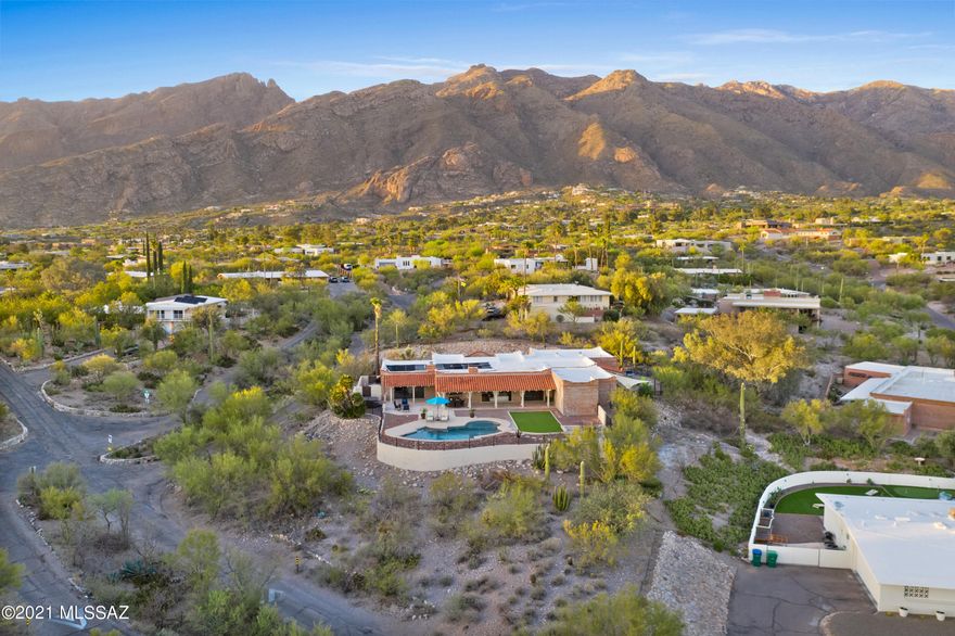 Perfectly sited on an elevated lot to capture Tucson's city lights and majestic mountain views, this hacienda style, burnt adobe home exudes all of the character one will find in a classic Tucson home. The circular driveway leads to an inviting front entry where you can see the city views from the windows. Inside, the foyer leads to a generous living room with wet bar, and wood burning fireplace. The open kitchen features a breakfast area, bar seating and opens to a large family room and outdoor patio space with incredible mountain views! True split bedroom floorplan, master bedroom with fireplace, sliding glass doors, and en-suite bath. The 5th bedroom is currently used as an office space. This home has it all: privacy, views, great bones, character, and the plantation shutters! This is the perfect home for entertaining! Extended covered patio that looks out to the pool and beautifully landscaped yard space with plenty of great spots for lounging. Enjoy the sunrises and sunsets from this incredible foothills residence.