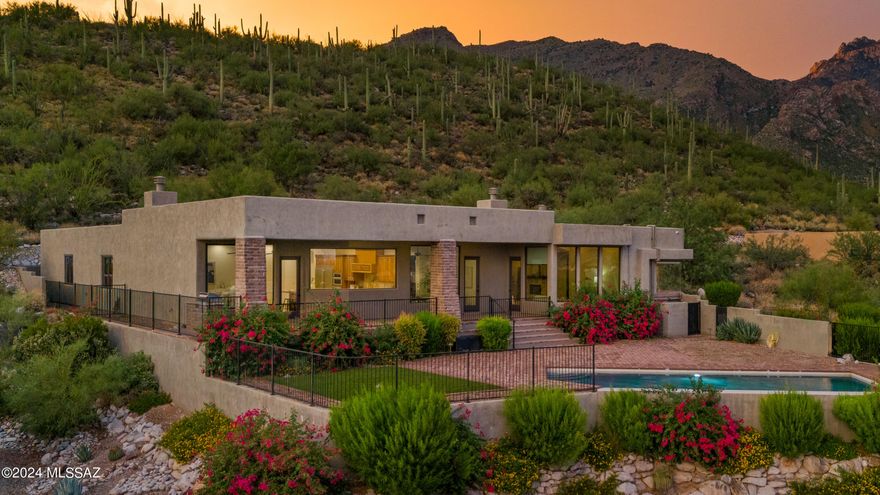 2016 custom desert contemporary residence on an elevated homesite in popular Alta Vista.  This 5-bed/5-bath home has sensational views of the city, mountains, & sunsets on a saguaro-studded lot.  Minutes from district #16 schools, Ventana Canyon Country Club, Sabino Canyon, Whole Foods, & more. Soaring 12' ceilings, walls of windows, wood-beam ceilings, natural stone, & light, airy spaces set the tone for this move-in ready home. Captivating views from every window of the city below & the mountains beyond. The mature desert landscape is bursting w/ color as you ascend the driveway lined w/ pavers. Large motor court & private entry w/ a custom wrought iron front door.  Exceptional city views greet you as you enter this open & inviting space with a stacked stone fireplace...CONTINUED The kitchen/great room/dining area has a wood-beamed ceiling, a Cantera fireplace, & a large frameless window in the kitchen that showcases the spectacular views from this high vantage point. The kitchen is complete w/ a center island w/ a breakfast bar, a prep sink, custom pendant lights, custom-built cabinetry, & SS Electrolux Icon appliances. Additional features include double ovens & a 6-burner gas cooktop w/ custom wood hood vent & pot-filler, granite counters & travertine backsplash. The dining area is positioned to capture impressive views & corresponds to the outdoor space for ease of enjoying indoor & outdoor living. The built-in BBQ is conveniently located just outside the kitchen. Enjoy the best of Arizona living from a big backyard with plenty of space without the upkeep. A massive, deep-covered patio lined with w/pavers spans the back of the house. This magnificent outdoor space is enclosed w/ a view fence. A gorgeous pebble-tec pool with a negative edge is surrounded by brick pavers & a space w/ low-care turf. Vibrant desert landscape pops with color but requires little water. The exceptional owner's suite is spacious yet warm & intimate, w/ a stacked stone fireplace, & new wood-look tile. Oversized windows display unobstructed mountain views from the quaint sitting area during the day & city lights at night.. Bright & open owner's suite bath has an exquisite frameless corner window at the soaking tub capturing exceptional views. Additional owner's suite bath features include a dual sink vanity, custom cabinetry, a separate shower, & a huge walk-in closet with w/custom built-ins. One bedroom, which could be an office or nursery, is adjacent to the owner's suite near the powder room. The west wing of the home houses a pre-wired theatre room ready for a home theatre/gaming room, an exercise room/yoga room, or whatever you may need. In addition, there are 3 en-suite bedrooms. One of the bathrooms has hall access as well. Next-level laundry room has a top-of-the-line washer & dryer, tons of cabinets for storage, counter space & a sink.  Oversized garage w/ epoxy floors has plenty of room for storage. Incredible foothills location w/the best lifestyle Tucson has to offer.  Top restaurants, shops, grocery stores & fitness options are minutes away.  For nature lovers & hikers, access incredible trails just moments from your front door & get to Sabino Canyon in a matter of minutes.