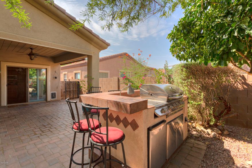Discover the fun lifestyle offered at Rancho Sahuarita. You will all enjoy swimming and splashing at pools, water park and splash pads. Toss the ball around at a neighborhood park, work out at the fitness center, swish through curves at the skatepark, go fishing or take a stroll around Sahuarita Lake. This single-story, three bedroom, two bath home features an inviting, open great room which adjoins the spacious kitchen and a comfortable dining area. Windows are dressed with plantation shutters. The laundry room includes a washer and dryer, additional built-in custom storage, a soak tub and a chest freezer. Host the ultimate gatherings at the outdoor bar and kitchen or sit and relax around the firepit and roast marshmallows.