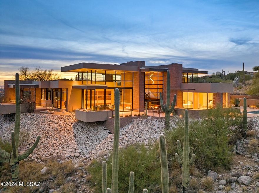 Immerse yourself in this spectacular Sabino Mountain home designed to capture every horizon.  This custom home by architect Kevin Howard highlights our Sonoran Desert landscape through walls of glass and the use of naturally textured materials. Interior spaces meet exterior verandas to enjoy panoramic city and mountain views from every vantage point. Entertain in the sprawling kitchen with gourmet appliances and sparkling city lights all around. The primary suite features a floating dual sink vanity, soaking tub, walk in shower, and private WC. Three additional bedrooms, each with an en-suite bathroom, an executive office on the second floor, and three fireplaces create a modern retreat that is as functional as it is elegant. An additional half bath for guests, copious storage, owned solar, and a heated pebble finish pool complete this extraordinary residence. Crafted of the highest materials quality and supremely situated, this residence is one to behold.