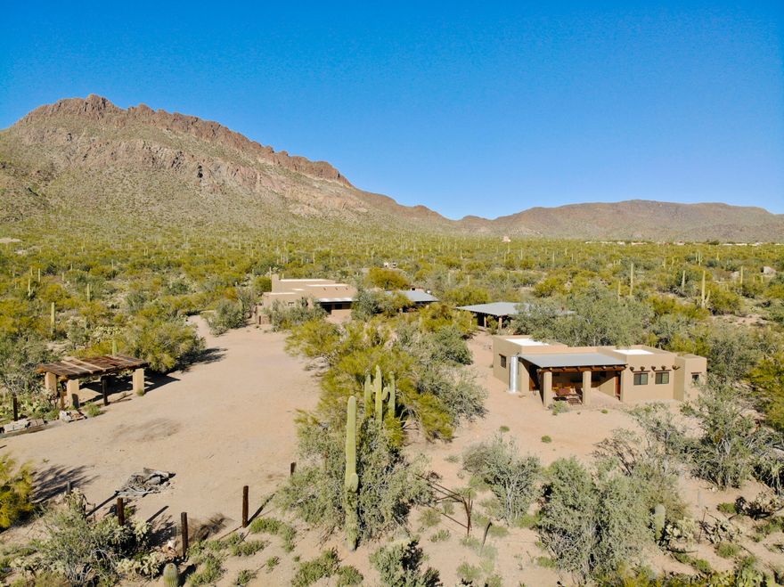 Southwest living doesn't get better than this one-of-a kind gated ranch property totaling 8 acres backing up directly to Tucson Mountain Park. Pictures can't do this property justice! Feel like you're living on a movie set with a luxuriously updated 3,200 sq. ft. main home looking at the gorgeous Tucson Mountains & featuring concrete, wood, & tile floors, soaring beamed ceilings, modern kitchen finishes, and unique territorial touches; a guest house with a full kitchen & living space; plus a ''bunk house'' studio with en suite bathroom. The property has endless possibilities as a full-time residence, bed & breakfast, or corporate retreat. The outdoor BBQ & patio spaces are truly a standout feature, and the main courtyard area could accommodate a pool or large events. Character galore!