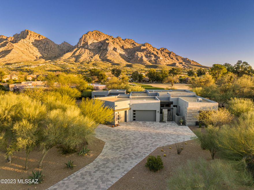 This gorgeous modern estate has arguably the best views in all of prestigious Oro Valley Country Club. Set on 1 acre of tranquil grounds this home includes stunning mountain and golf course views through the giant wall of windows.  The precise landscaping has perimeter hedges, contemporary travertine walkways and terraces that allow for great entertaining and outdoor enjoyment. In addition this home boasts an oversized three car garage with 500 square feet of heated and cooled flex space not included in the listed square footage. Other amenities include high ceilings, motorized shades, workshop/golf car garages, built in bar, gas fireplace, security system, newly constructed SwimSpa with solar, citrus trees, circular driveway and a private iron door entry. Come enjoy the good life!