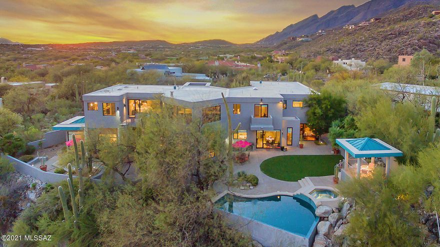 This stunning contemporary masterpiece w/ detached guest house is sited on 1.29-acres. Nestled against the Catalina Mountains, this is a true hidden gem that effortlessly showcases Tucson's beautiful city & mountain views. Enter home to an open floorplan w/ spacious living areas & contemporary design by John Campisano. This 6,566 sq. ft. estate has towering ceilings & walls of windows allowing plenty of natural light & divine mountain views. Entertain in kitchen w/ marble counter tops, upgraded appliances, & spacious walk-in pantry.  Luxury amenities abound w/ an intricate maple spiral staircase invites the upper level's 5 beds, all en-suite, where each room is paired w/ individual balconies & large closets. Seamless indoor-outdoor flow to backyard with resort-like spa/pool, BBQ, & Ramada.