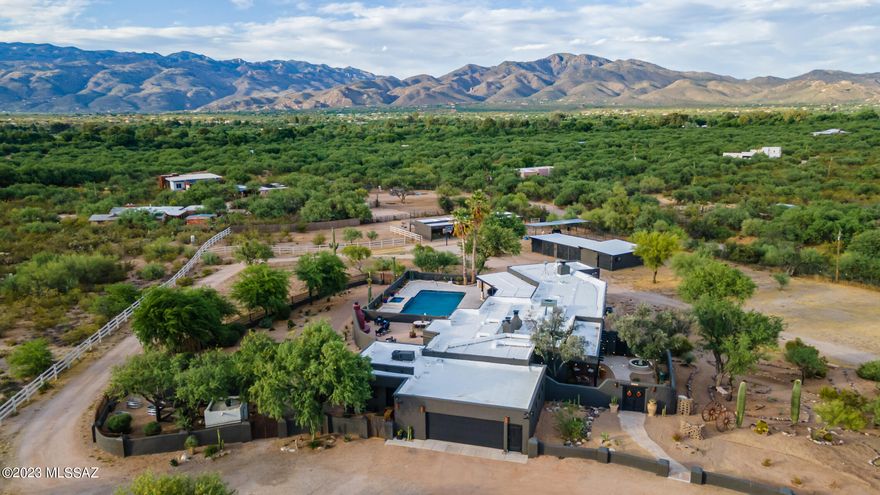 Welcome to this historic adobe & concrete block constructed estate sitting on 4.25 acres surrounded by unobstructed mountain views with direct wash access. The main residence, guest house, 5 bay garage/workshop (mancave) 4-stall block equestrian barn, tack room, 3 additional covered stalls, turnout  have all been thoroughly & lovingly updated with modern conveniences while retaining the historic charm. All of the hard work has been done including updated electrical, plumbing, windows, roof, HVAC and tankless hot water heater. This home is located in the A+ rated Tanque Verde School District and allows you to enjoy the charm of country living while only being 2 miles from shopping, dining & so much more! Connected to both city water and a private well. The main home features hand hewed beams from Mt. Lemmon along with custom doors throughout, added by nationally recognized local builder Mark Butler. The outdoor living space is a desert oasis that has been refreshed for the ultimate entertaining. Spend time relaxing by the pool or shoot some hoops on the basketball court. This property is a horse lover's dream and has direct access to the wash for miles of trail riding, hiking & biking into the Saguaro National Forest. Along with the wash access, there are 4 indoor/outdoor stalls that offer a significant temperature difference on the hot summer days & cool winter nights. These 4 stalls have automatic waterers in all paddocks & open directly into a newly fenced turnout. There are 3 additional spacious covered stalls. The newly constructed chicken coop is within the fully fenced in backyard for easy access to fresh eggs. Additional custom iron fencing provides ample space for the dogs to run & a second layer of protection for the chicken coop.