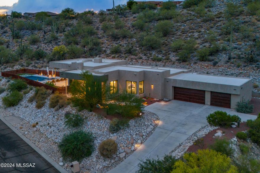 Welcome to an exquisite sanctuary in the prestigious and gated Sabino Mountain community. This modern Sonoran masterpiece is designed to captivate with its breathtaking views, elegant modern architectural features, and flair.

Upon entering, you are greeted by expansive window walls that perfectly frame the awe-inspiring vistas of the Catalina Mountains, shimmering city lights, and the distant beauty of the Santa Rita Mountains. This home offers a seamless blend of indoor and outdoor living, with designer lighting and stained concrete flooring throughout, enhancing its sophisticated ambiance. Spanning 4 bedrooms and 3.5 baths, this residence ensures comfort and privacy. Three of the bedrooms feature en-suite bathrooms, providing a lavish retreat for family and guests. The expansive master suite features his-and-her custom closets, and a luxurious bathroom equipped with a free-standing tub, a walk-in shower, dual vanities, and a dedicated make-up station.

The heart of the home is its state-of-the-art kitchen, meticulously designed for the culinary enthusiast. It features top-of-the-line Viking stainless steel appliances, a custom built-in coffee bar, a massive waterfall island, quartz countertops, and a butler's pantry. This space seamlessly transitions into the living area with a full wet bar perfect for relaxing or entertaining by the stylish fireplace - all while soaking in the magnificent views. 

Step outside to your private oasis via 10ft multi-panel doors that open to the patio where luxury knows no bounds. The backyard is a paradise with a sparkling pool and temperature-resistant pavers, ensuring comfort and style under the Arizona sun. Entertain family and friends with ease using the outdoor pizza oven and grill, perfect for al fresco dining.

Experience the epitome of luxury living at 4131 N Sunset Cliff Dr., where every detail is curated to offer unparalleled comfort and elegance amidst the stunning mountain backdrop. Your next chapter starts here!