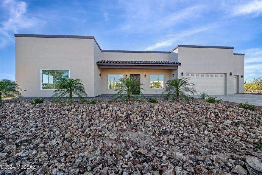 This home is a gorgeous sanctuary among the beauty of the Tucson desert. With high ceilings and open area to create the dream home you have been waiting for. The home has beautiful tile flooring and stone countertops throughout. Split spacious 4 bedroom floor plan with 3 bathrooms equipped with Bluetooth in the mirrors that illuminate stunning lighting with a background of an exquisite blue accent light. The bedrooms have immense walk in closets with built in shelving units. The laundry room is a large spacious room within itself. Heading into the 3 car garage, you will find an enormous amount of storage along with an outlet to charge your electric car. Backyard is equipped with built in BBQ, refrigerator, sink, and ceiling fans for your enjoyment overlooking the natural desert beauty!