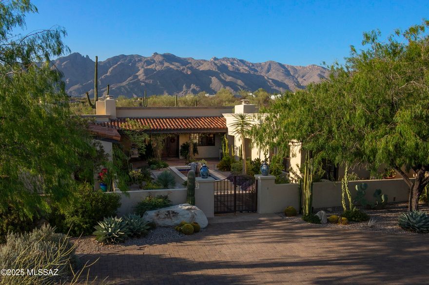 Gracefully positioned at the terminus of a quiet cul-de-sac within the distinguished, guard-gated community of Catalina Foothills 10, this private residence rests atop a 1.9-acre hilltop, commanding unobstructed vistas of the Catalina Mountains by day and a tapestry of city lights by night. Rooted in the regional architectural vernacular and inspired by the enduring soul of San Miguel de Allende, the home reflects a studied balance of old-world romance and regional expression. Approached by a gently winding paver drive, the home reveals itself through a formal motor court that opens onto an enchanting entry courtyard, centered by a tiered fountain and framed by an outdoor fireplace. The architecture unfolds in a classic central courtyard configuration, allowing nearly every principal room to engage with the outdoors through deep, shaded portals and view-framing arcades.

Spanning 3,349 square feet, the residence is a testament to thoughtful craftsmanship and timeless materials. Hand-hewn mesquite cabinetry, vibrant Talavera tilework, and exposed wood beams lend an air of authenticity, while every room is imbued with natural light and quiet grandeur. The interiors offer four bedrooms plus a dedicated office, arranged in a split plan to provide both privacy and harmony of flow.

At the heart of the home lies a warm and welcoming kitchen, anchored by a center island and a hearth-style fireplace. This gathering space opens effortlessly to a charming breakfast nook and a sun-kissed BBQ terrace, where meals and moments spill gracefully outdoors. The adjacent living and dining spaces are equally inviting, scaled for both quiet evenings and entertaining alike.

The primary suite occupies its own distinct wing, designed as a serene retreat that balances openness with privacy. A fireplace anchors the space, providing warmth and a subtle focal point without overpowering the calm atmosphere. Direct access to the spa creates a seamless connection between indoor comfort and outdoor relaxation. Adjacent, a custom library or study offers a quiet, well-lit workspace that supports both reflection and productivity. Generous in scale yet restrained in detail, the suite reflects a considered approach to living, where every element is intentional, materials are authentic, and a sense of calm prevails.

Situated on the opposite end of the residence, the secondary bedroom wing unfolds with an air of quiet grace, thoughtfully arranged around a flexible central room that invites relaxation, study, or intimate gatherings. Each of the two bedrooms opens directly onto its own private courtyard, a secluded outdoor sanctuary defined by stucco walls and lush landscaping, where morning light filters gently through leafy canopies and cool breezes stir the air. These courtyards, extending the living space beyond walls, embody the seamless indoor-outdoor living so integral to the Spanish Colonial tradition. The bedrooms themselves are generously proportioned, with tall windows and doors that frame serene views and invite the natural world in. This wing offers a harmonious balance of privacy and connection, creating a peaceful retreat for family or guests alike.

A rare offering of architectural integrity and enduring charm, this residence is more than a home, it is a legacy property, artfully composed and ideally situated within one of Tucson's most esteemed communities.