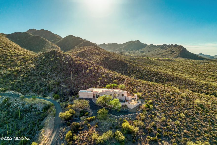 Situated on a commanding hilltop, bordering the Tucson Mountain Park to the North, with soaring city and mountain views stretching out over the valley below. A full end to end view of Catalina Mountains creates the perfect backdrop from which this homesite was selected. Maximizing the home's dramatic relationship between interior and exterior spaces is achieved through careful design and placement of structure, with connectivity to the surrounding landscape. Exterior transitional spaces are rich in mobility with the capacity to enjoy and entertain being effortless, emphasizing walls of glass that extend through the interior and outdoor living spaces. Stargaze from the rooftop deck, or enjoy the quiet simplicity of life relaxing next to the koi pond, observing the procession of wildlife. Enter into a high design interior space that complements and reflects the vernacular, where you are greeted by a large foyer acting as the central hall. The informal living room is sequestered on the Southeast end of the residence featuring large picture windows that allow natural light to fill the space, establishing the main connection point of the home. The floor plan comprises both formal and informal living spaces, equally suited for scaled entertaining, as well as quiet moments, with a chef's kitchen that boasts custom cabinetry, pro series stainless steel appliances, ample storage and functional counter space, with every measurement and detail having been efficiently considered to enhance the user experience.
The private East wing features the sumptuously appointed primary suite, with a large walk-in dressing closet, dual vanities, fitted with alder cabinetry, dressed in stainless fixtures, large soaking tub, and walk-in shower. Two additional secondary suites are featured on the Northwest end of the home, privately situated and perfect for family, or guests alike.
Seamless indoor-outdoor entertaining while out on the sun-drenched East facing terrace, offers al fresco dining, with a dedicated built-in barbecue station, dining area, and a series of patios and exterior living spaces that create a succession of courtyards resulting in varied focal points. The outdoors unwind like a garden narrative of texture, light, and mood, with every comfort having been considered and detail meticulously crafted, the result being a home that offers a sense of ease to enjoy the Arizona Lifestyle.