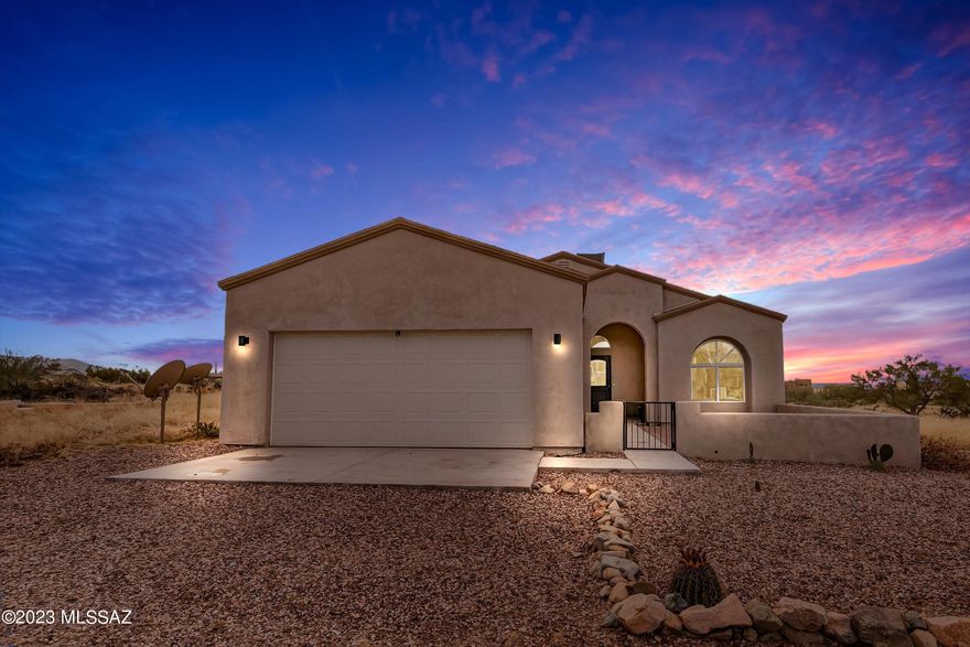 Built in 2021, this home offers amazing views, open spaces and NO HOA. Nestled off Sahuarita Rd, on a short dirt road, the property feels remote, yet is only 15 minutes from shopping and dining. The home greets you with an enclosed patio perfect for a bistro table to enjoy the sunrises and mountain views. Step through the elegant front door and you're immediately impressed with the custom travertine tile, warm neutral colors and open concept living. The kitchen boasts stainless steel appliances, a farmhouse sink, richly colored dark cabinetry and granite countertops. The spacious primary suit has access to the patio, & a large en-suite with dual sinks, a walk in tiled shower and a jacuzzi tub with elegant surrounds. The back patio has open desert land & captivating mountain views.