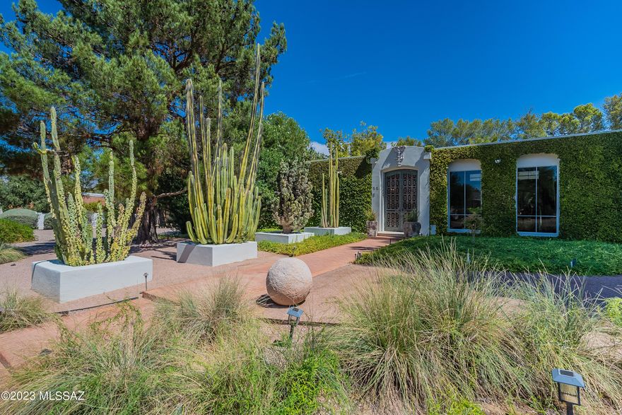 Introducing a master class in design and effortless beauty. Don't miss this unique home inspired by nature and fearless architectural lines, this home site is unique to Tucson's rich history. Craft-fully designed by the homes owner's along side notable landscape architect Guy Greene, immense pride of ownership has remained since its inception. The feeling is inevitable once you arrive. Fresh gardens and fig vine greet you and hug the picturesque facade, The steel and bronze gates welcome you. A wonderful alcove entry with arched alder doors then lead you to a wood beam lined great room, the perfect place to bring your guests and friends. With two large master suites and two flexible spaces the home offers different options for lifestyle. Kitchen and dining are classy and functional. Detail galore! From the faux finished walls and mirror lined dining room, to the concrete floating hearths and silver/gold leaf ceilings all to be admired. Limestone tiles run consistently throughout this one level home adding cohesion and elegance. Natural light is on display at all hours of the day creating a magnificent indoor/outdoor flow. The livable Atrium at the heart of the home allows access from all rooms and an open door or window creates refreshing cross breezes that further exemplify the thoughtful design. A study offers tapestry clad walls, custom built-in alder cabinetry and an en-suite bathroom that exudes luxury and timeless elegance. The generous primary suite features a large fireplace and floor to ceiling windows with views of the secluded backyard. The primary bath offers a jetted soaking tub, multiple walk-in closets, double vanity, custom makeup vanity and is clad in cut marble. The secondary suite includes a large bath with black honed quartz counters and two basins. Rounding out the rooms is a flex space (currently used as an office) that offers another en suite bath that is marble and mirror lined floor to ceiling. The home is wrapped in non-invasive Fig vines creating incredible curb appeal and lush backyard landscape that's a show-stopper! An architectural steel ramada perfectly rests between the pool and grass landing offering a place to lounge and play. Parking is also generous with an aggregate and brick motorcade, as well as a formal and finished 2-car garage that could be purposed for fitness or studio use. Designed to entertain, the outdoor spaces of this ultimately private residence is truly bar none. A wonderful property and opportunity within reach of the U of A, Banner Medical and the Arizona Inn all together in the heart of Tucson.