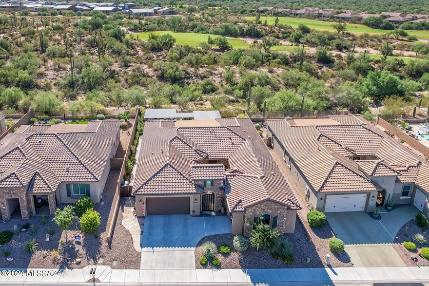 Luxurious 2BD/2.5BA +Den (2,514 sq ft) home boasts a gated front courtyard with fountain, guest wing off courtyard with den/office, plus spectacular rear oasis backing to large common area off golf course for privacy. Stacked stone facade with decorative entry gate flows to open concept gathering room with media wall, surround speakers and retractable glass sliding doors to enjoy indoor/outdoor living. Gourmet kitchen with butler's pantry showcases curved center island, breakfast nook, granite countertops with decorative tiled backsplash, plus stainless appliances including 5-burner gas cooktop. Walk-in pantry and laundry are enclosed by sliding barn doors. Second den or formal dining room lies off foyer. Elegant Owner's suite accesses rear patio with hot tub and hosts a sleek bath with dual vanities, granite countertops and elongated walk-in rain shower. Guest bedroom offers a Murphy bed and en suite bath with tiled shower and walk-in closet. Relax or entertain in the phenomenal rear yard boasting covered patio with stacked stone fireplace, raised patio with elongated BBQ station, beverage fridge and bar seating, linear waterfall feature, outer dining area, metal shade pergolas with louvers, plus raised hot tub patio, decorative turf, outdoor speakers and peeks of several mountain ranges. Additional amenities include gorgeous vinyl plank flooring, ceramic tiled baths and carpeted guest den, plus powder room, tray ceilings, tankless water heater, water purification system and split garage bays (2+1). This 55+ active adult community in desirable Del Webb at Dove Mountain lies just beyond the Ritz-Carlton Resort and within a short distance of hiking & biking trails. Perfect for the most discerning buyer!
