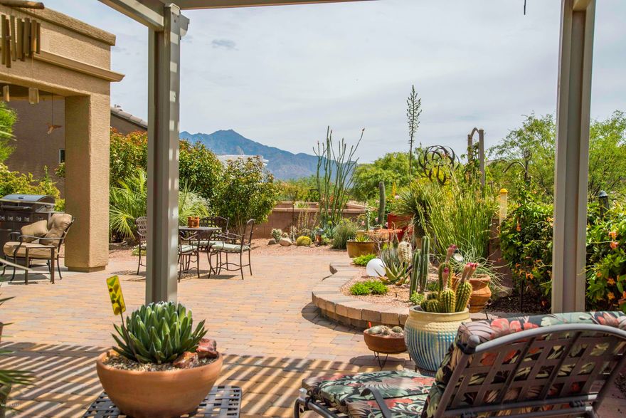 Twin giant palms amid an array of desert cacti provide great curb appeal and your front patio will provide views of the Santa Rita mountain to watch gorgeous sunrise and sunsets.  Enter into the great room with beautiful ceramic floor tile and an apportioned living space centered on a gas log fireplace with adjacent media/art niche.   Contemporary curved pony-wall architecture wraps the incorporated den for separation and relaxation.  The kitchen features attractive Corian countertops in warm earth tones with a custom tile backsplash, a Chef's gas range and under-counter stainless sink with a single handle gooseneck faucet.  The master bedroom suite is filled with natural light beaming through bookend windows while the bath offers comfort and space with separate his and hers vanities. Your outdoor patio lifestyle is enhanced by mountain views from an open-air Ramada where you'll can relax under a cool breeze.  A truly botanical experience displaying numerous vegetation species within island gardens surrounded by brick pavers and rock accents.  This adorable home sits in unique location on a larger, cul-de sac lot giving you the everything you are looking for and a bit more elbow room!