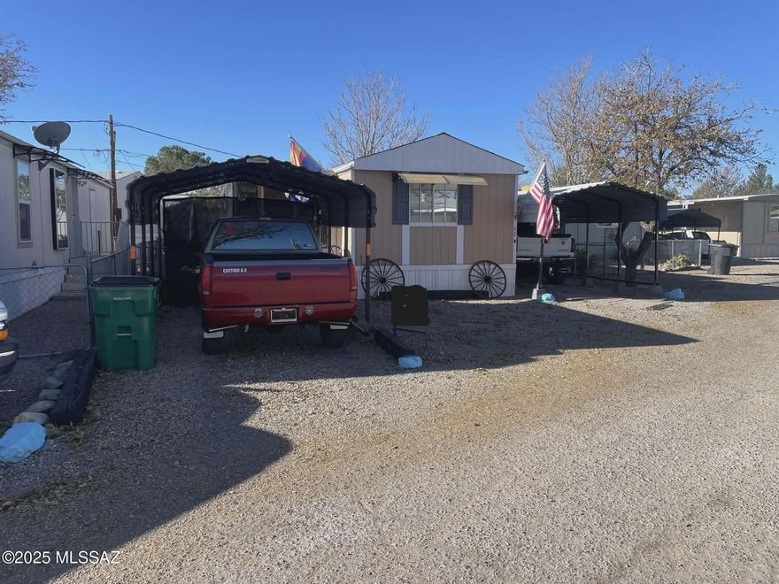 This well-maintained 2-bedroom, 1.5-bath manufactured home is located in a quiet 55+ park on leased land, with lot rent at just $400/month, including water sewer and trash also includes 6 months of prepaid lot rent and a transferrable home warranty. The home features a spacious screened-in Arizona room, perfect for relaxing or entertaining year-round. Enjoy outdoor living with a full outdoor kitchen, new gutters, and security lighting for added peace of mind. With three carports and space to park up to four vehicles, there's room for all your guests. The beautifully landscaped yard showcases native cacti and large shade trees, creating a low-maintenance desert oasis. A convenient shed provides extra storage. Ideally situated close to shopping and other local amenities.