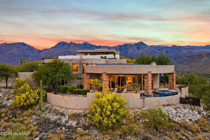 Views that this house offers are like no other! Enjoy City Lights AND Mountain Tranquility at once.  This Contemporary, Luxurious home sits perched above the Tucson Valley. Floor to ceiling windows with mostly automatic shutters and an open floorplan creates a feeling of seamless indoor and outdoor living.  Custom kitchen has quartzite counters/Island, Banco sink, Stainless Steel Viking and GE Profile appliances & Alder + Mample Cabinets.  Primary suite features fireplace for cozy Tucson nights, spacious yet functional bathroom, exercise/office with door leading to a balcony.  Washer and Dryer in primary closet for convenience!  Three ample size bedrooms downstairs, two with ensuites, custom built ins, walk in closets.  Security shutters on two of the bedrooms downstairs, Owned Solar Panel.   Backyard is an absolute oasis with wrap around patio, infinity pool overlooking the city, yard areas on both sides.  Please see documents for all the features of this home