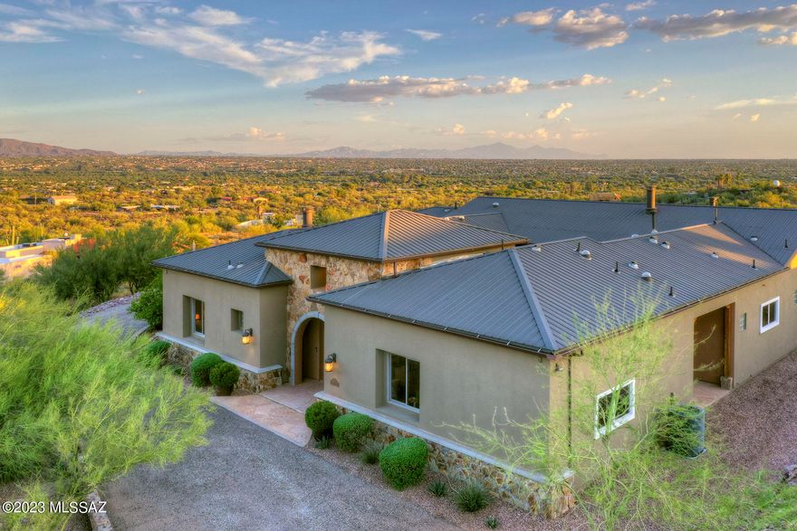 This stunning Southwestern contemporary is high on a hill and offers sweeping views of the mountains & sparkling city lights. This 4,715 sq. ft. ridge-top home is located on a 3.35 acre desert lot. Highlights of this 5-bedroom, 4 ½-bath residence include a grand foyer with a 16' soaring ceiling, views from most room, polished & scored concrete flooring, high ceilings, wood-casement windows, cherry wood doors throughout, and an oversized 3-car garage. The spacious living/dining room offers a 12' ceiling, a dramatic stone fireplace, a wall of glass framing city & mountain views, and access to an expansive porch & stone fire pit. The generous family room, open to the kitchen, features a high 12' ceiling, a stone fireplace, and access to the covered back patio & the central courtyard. The fabulous chef's kitchen provides scored concrete flooring, stainless steel appliances including a professional gas range, alder cabinetry, thick granite countertops, a breakfast bar, and a generous walk-in butler's pantry. The gracious primary suite has a floor-to-ceiling stone fireplace, a large customized primary closet with a washer/dryer, and a luxurious bathroom with dual vanities, seperate shower & a spa tub. The charming center courtyard offers a fireplace and is ideal for lush plantings. Enjoy the back patio offering two covered porches, flagstone walkways, a 55' lap pool, a gazebo and panoramic views. Additional features include 2 septic tanks, 3 HVAC zones, a metal roof and so much more.