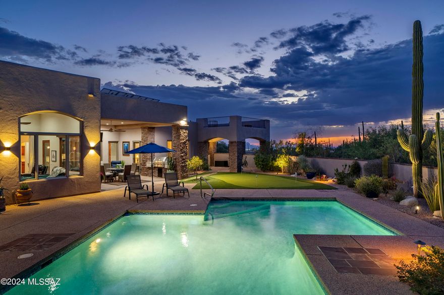 Located in the heart of Pima Canyon Estates, this traditional Southwestern home is designed to harmonize with the desert landscape, blending architectural form defined by stucco volumes, accented by natural stone cladding that anchors the home to its high desert surroundings. Deep roof overhangs provide both visual interest and practical shading, with North/South orientation reducing thermal gain while maintaining expansive, unobstructed views of the Catalina Mountains. Native plantings surround the structure, offering a visually compelling and low-maintenance environment, while enhancing the home's connection to its surroundings. Approaching the residence, the motor court is both functional and discreet, bordered by native mesquite trees and desert shrubs, which offer privacy without sacrificing the home's subtle elegance. The entry courtyard is served by a porte-cochère, creating a transitional threshold between the exterior and interior living spaces. Carefully positioned walkways of exposed concrete quietly reference the natural textures of the landscape, setting the tone for the interior experience, while guiding visitors toward the custom steel and glass entry door. 

Upon entry, the home's layout is organized around a central axis, emphasizing flow and sightlines that connect key living spaces to the exterior. Soaring ceilings accentuate scale, while large expanses of low-emissivity glass provide natural light without compromising energy efficiency. The interior finishes are refined yet restrained, with Travertine floors that float seamlessly throughout the space, juxtaposed against soft wall accents and materialsselected for their tactile qualities and timeless appeal. 

The kitchen exemplifies form and function, with custom cabinetry providing a warm backdrop to the space. Granite countertops and a seamless integrated backsplash offer visually uninterrupted surfaces, while high-end appliances are celebrated through thoughtful integration. A central island, topped with natural stone, serves as both a functional workspace and an informal gathering point, reflecting the kitchen's dual role as a culinary and social hub. Soft, indirect lighting enhances the material finishes without overwhelming the space.

The primary suite is designed as a private retreat, positioned to capture sweeping views of the Catalina Mountains, while ensuring the utmost privacy. The bedroom's proportions are generous, with floor-to-ceiling windows that blur the line between interior and exterior. In the en-suite bath, spa-like amenities are incorporated with a traditional aesthetic, featuring dual custom vanities, walk-in shower enclosure, and a freestanding soaking tub. The bathroom's design promotes tranquility through the use of natural materials, and a thoughtful layout that prioritizes the home's occupants. 

One of the property's many on-site amenities includes a fully integrated and privately owned electric solar system, representing a forward-thinking approach to energy efficiency and sustainability, while also reducing the home's operational costs.

The exterior spaces are as meticulously crafted as the interior, with the pool area offering a seamless continuation of the home's architectural narrative. An integrated pool and elevated spa reflects its surroundings, creating a visual connection to the distant mountains, while the adjacent terrace provides shaded outdoor living spaces through the use of deep cantilevers. Low-profile landscaping complements the architecture without competing with the panoramic vistas of the Catalina Mountains, which serve as a breathtaking natural backdrop. Discreet lighting enhances the space at night, allowing the views and architecture to remain the focal points for one to enjoy the Arizona Lifestyle.