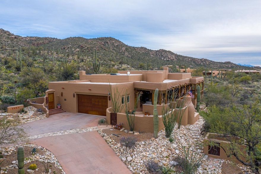 Scenic Santa Fe beauty located in the backdrop of the Catalina Mountains, panoramic and city views abound from this southwest treasure.   Not one detail overlooked.  Large covered patio with wood accents, chimea & spa overlooking the Tanque Verde valley. Front courtyard.  Wood ceilings w/vigas throughout  Living rm boasts round room, fireplace w/bonco seating, formal dining room, cozy family room open to kitchen. complete with custom cabinets, wine fridge, breakfast bar. Master bdrm with wood celings, mexican tiles. secondary bdrms have step-in closets.  Income producing 1 bdrm, 1 bath guest house, with private balcony  Over 5 acres, horse facilities, 3 stalls arena. Studio/workshop located next to guest quarters. Meticulously maintained, one owner.  Southwestern accents thruout