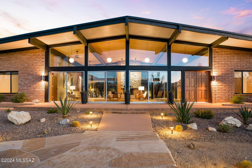 Welcome to this exquisitely revitalized Mid Century Modern masterpiece, a true architectural treasure in the iconic Frank Lloyd Wright style.  Designed by renowned architect, Floyd L. Cullop, and built in 1967, it is nestled on a sprawling 3.33 acre lot.  The home offers direct access to the captivating Saguaro National Monument East, which is just blocks away.  This remarkable, absolutely one of a kind property harmonizes classic design with modern luxury, encapsulating the essence of Tucson's distinctive architecture.  This iconic architectural gem features original burnt Adobe brick post-and-beam construction throughout,  Located in the highly sought after community of ''The Notch'', the property presents breathtaking panoramic mountain views. Where nature's beauty unfolds in every direction, offering spectacular sunsets and the serene presence of over 100 majestic saguaros gracing the landscape.  Inside, the home boasts 5 elegantly appointed bedrooms, each designed to provide comfort and tranquility.
The 3 completely remodeled and upgraded bathrooms are a testament to  modern craftsmanship, featuring high-end fixtures and finishes that seamless marry style and function. For ultimate relaxation, enjoy the infrared sauna, tucked away in the primary bathroom, a spa-like retreat right at home.  The interior celebrates Mid Century Modern aesthetics with a flair, highlighted by soaring ceilings in the expansive 1,100 sq. ft. great room.   The dramatic natural stone gas fireplace serves as a stunning focal point, inviting warmth and ambiance to gatherings, intimate family moments and holidays.  The kitchen is a culinary enthusiast's dream, showcasing extraordinary walnut cabinetry in true Mid Century style, equipped with state-of-the-art KitchenAid appliances, including double ovens, 36" cooktop, sleek dishwasher, counter-depth refrigerator, as well as  a 140 bottle dual-zone wine refrigerator, striking quartz countertops that shimmer with elegance.  This home is outfitted with all new dual-pane windows and doors, ensuring energy efficiency while allowing natural light to flood the living spaces.  The entire property has undergone a complete electrical upgrade, featuring a new 400-amp panel, enhancing the home's functionality.  Additionally, a brand-new multi-zone heating and air conditioning system ensures year-round comfort.  All floors were refinished with a classic cement for ease in cleaning.  New garage doors were added as well a a brand new driveway.
The professionally designed backyard is an entertainer's paradise, with lush Patriot turf, a custom 12x18' steel pergola that provides the perfect shaded retreat, and new irrigation systems paired with outdoor landscape lighting.  At the heart of the outdoor oasis is a fully renovated pool and deck, complemented by new pool equipment, inviting you to indulge in refreshing swims under the warm Arizona sun.  This home is not just a place to live, it is a masterful blend of design, comfort, and nature, offering an unparalleled lifestyle that truly represents the pinnacle of modern living in Tucson.