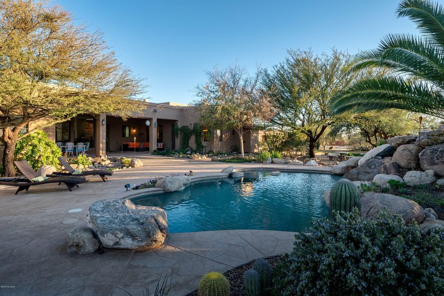 This dramatic hideaway, situated on over 4 acres, creates a strong spatial connection between the home and the surrounding landscape. Upon arrival, an air of grandeur pervades this incomparable Masonry built residence. Privately located and surrounded by sprawling mature desert landscape, adds to the feel of this sophisticated estate. Entering the residence, you are greeted by a large foyer with soaring ceilings, acting as the central hall, establishing the main connection point of the home, which opens onto the formal living and dining rooms. Complementing this perfectly executed floor plan, lofty ceilings and walls of windows opening onto the tranquil grounds at every turn. Designed to substantial scale and comfort, allowing versatility in its use to reflect the activities enjoyed, with the heart of the home being the fabulous chef's kitchen with gorgeous custom finishes throughout, overlooking the family room, with a fireplace and breakfast dining. Sequestered on the South wing of the property is the sumptuously appointed master bedroom, with dressing suite, luxuriously finished master bath and large office/workout (flex) space, with one additional bedroom located on the South wing. The balance of three bedrooms are located on the North wing of the residence, each with direct access to an adjoining bath, perfect for families and guests alike. 

An elongated veranda connects the shared living spaces, with a series doors coordinated to tie the interior rooms to the spacious outdoor living environments, resulting in a juxtaposition of private and social spaces. Layers of elevated patios, with various native shrubs cause an explosion of color, light and shadow, creating a framework for the pool and spa, acting as the centerpiece of the rear courtyard. 

Enjoy the 1,500 sq ft ancillary building, which was independently built on the Southwest end of the property, that can be utilized as an additional 3 car garage (for a total of 5 cars including the two car garage connected to the main residence), equipment and/or overflow storage opportunity.

Seamless indoor-outdoor entertaining while out on the sun-drenched terrace, offers al fresco dining, with multiple Koi ponds, with a selection of fruit trees perpetuating the eating local, sustainable foods trend right in your own backyard garden, all of which overlook the resort like pool and spa, with the unobstructed Catalina Mountains and Sunset views beyond.