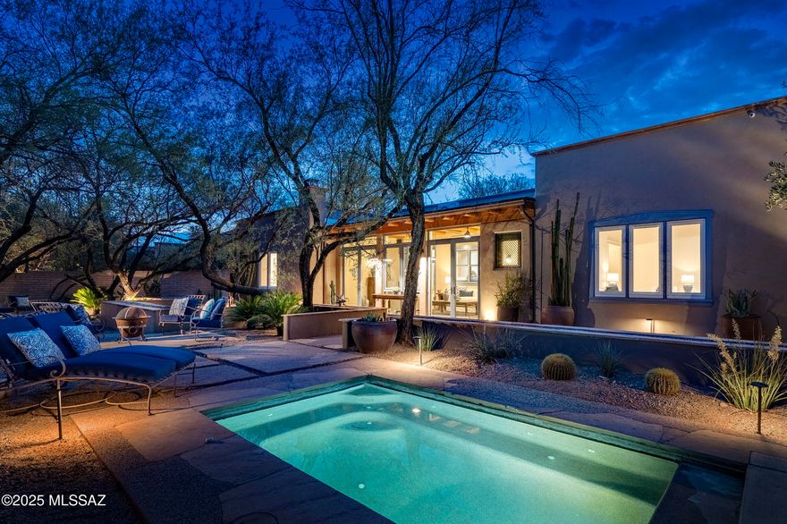Nestled within the storied enclave of ''Adobes del Bosque,'' one of Tucson's most architecturally significant communities in the historic Fort Lowell District, this authentic mud adobe residence is a reverent expression of regional craftsmanship and timeless design. Built using stabilized earthen materials and traditional methods, the home stands as a masterclass in architectural integrity, gracefully merging historic form with the understated luxuries of modern life. Enter through a serene, walled courtyard, a quiet procession that opens to 3,064 square feet of richly composed interiors. The material palette is both grounding and elevated, with sixteen-inch-thick adobe walls offering mass and thermal performance, while smooth plaster surfaces lend a tactile sense of calm and continuity. Design here speaks softly in a vernacular of warm authenticity, where concrete floors, natural pigments, and earthen textures engage in a quiet dialogue with shifting light and shadow.

Inside, soaring wood-beamed ceilings span the great room, structural poetry rendered in the language of the Southwest. Natural light filters through deeply inset windows and a procession of doors, animating a sequence of intimate, elegantly scaled spaces. True to its origins, the home is aligned along a north-south axis, harmonizing both form and function with the rhythms of the desert.

The kitchen is soulful in its simplicity. Knotty alder cabinetry in a honey-toned finish offers an organic richness, contrasted by sleek stainless steel appliances. The space opens seamlessly to the adjacent dining area, inviting ease, connection, and conversation. Every detail is expressive, with arched niches, hand-hewn wood beam vigas, and rough-sawn fir plank ceilings speak to a legacy of craftsmanship and material honesty.

Privately situated in the west wing, the owner's suite is a study in retreat. A corner fireplace grounds the room in warmth, while generous scale and clean lines provide clarity and calm. The walk-in closet is discreetly integrated into the suite's design, while the bath pairs dual sinks with polished fixtures, a walk-in shower, and a towel-warming drawerdetails that whisper indulgence without excess.

Outdoors, sunlight drapes across curated patios and garden paths, culminating in the shimmer of a sun-drenched spool beside an elegant fireplace. This is a landscape composed in layers, where indoor and outdoor spaces blur through covered portals, rhythmic shadows, and deeply considered sight lines. A place of quiet reflection, architectural legacy, and enduring beauty.