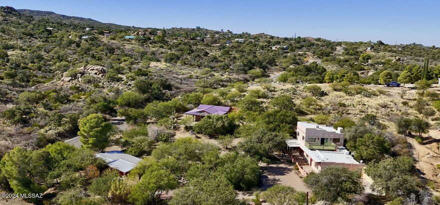 Entering into this over an acre property, past the pine and fruit trees, up the paver driveway and garden beds, you are greeted by ample outdoor space and 3 homes allowing for potential for multigenerational family living, or a tranquil rental retreat. The main home is a charming rustic Santa Fe style and features a front courtyard, multiple living areas, many wood accents, stone floors, and a wood burning fireplace. There is one bedroom downstairs and a spacious suite upstairs with a large deck and Mountain views. There are 2 guest homes on the property. (All 3 are situated allowing for privacy from the other homes.) One, recently completed, made with rammed earth. Both guest homes feature wrap around patios, metal roofs and many special accents. This property is truly one of a kind.