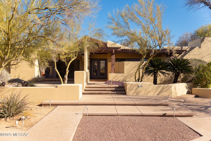 Wonderful contemporary estate designed by renowned architect David Tyson!  This serene and beautiful, walled compound celebrates the seamless blend of indoor and outdoor living spaces, a signature of Tyson's designs and love of nature. Upon entering the main residence, guests are greeted by a soaring wooden cathedral ceiling framing a large expanse of glass, and an intuitive flow of open rooms and private spaces.  As you wander through the home, each space reveals picturesque garden vignettes, private patios and ramadas, the resort style pool with relaxing fountain, separate spa, a mature canopy of trees and fragrant, flowering gardens. The main residence has a split bedroom plan with a peaceful, large primary suite showcasing a dual-sided fireplace and sitting room overlooking the pool, spa and private side garden. A lovely chef's kitchen boasts gorgeous millwork and a large pantry with  2nd refrigerator, standing freezer and wine cooler.   The elegant great room and dining room share a fireplace and each opens to patios, which creates excellent flow for entertaining.  You will find an additional 2 bedrooms and 2 full baths, as well as a family room/game room and another office with a private, covered patio. 
A large guest house is situated across the manicured, enclosed gardens. Within you will find a large great room, kitchenette and full bathroom, and a large formal library/study lined with bookcases and a sliding ladder. This building also houses an extensive woodworking shop, with all of the bells and whistles included with the sale of the property. 
This rare and delightful property offers the ultimate desert retreat within the quiet enclave of Paseo De Los Altos, a unique treasure within the city. Conveniently situated in the foothills near to Tucson's finest dining and shopping, and close to downtown's arts, theater and nightlife, the Loop,  UA and the best of the Sonoran Desert lifestyle.