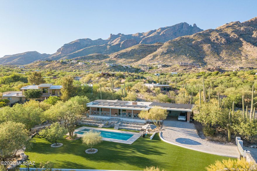 Absolutely stunning 1964 burnt adobe classic in the heart of the Foothills, with the kind of picture perfect outdoor living spaces, views, and visual impact that transcend.  A synergy of natural elements, clean-lined design, and materials that must be seen to be fully appreciated.  Surrounded by hand-crafted native-stone walls, stunning terrain-scaping, and the kind of views that stop people in their tracks, this 3 Bedroom, 2 bath original feels every bit like a slice of paradise, all without losing a shred of authenticity.  Brilliant pool and landscaping transformations feel at once new, yet in complete harmony with the original character of the home, the mature trees, and the natural desert foothills surrounds.  See extended description, virtual tour, and full aerial/walkthrough video. With care taken not to alter the original aesthetic of this mid-century gem, the exterior spaces of the property have undergone a complete transformation, elevating them in every way.  An absolute knockout, aesthetically, but more than that--a home that lends itself to the enjoyment of nature, friends and family ... and moments of quiet solitude inside and out.  As good as it looks in images, it feels even more special in person.  
What's remarkable here is that, as a property in this market, it represents a rare opportunity to enjoy a huge and perfectly executed outdoor space in the heart of the upper Foothills without having to take on the "too-big" house that often goes with it.  On a prime spot in the quiet mid-point of beautiful Coronado Foothills Estates, only a hundred yards or so down from a neighborhood-owned natural space, it's easy to see why this smartly designed and true-to-its-roots '64, sited on a subtle rise, was the perfect canvas on which to paint an outdoor-living masterwork.  Neat as a pin, with the sublime balance of wood beams, burnt adobe, and clean white walls in every space, an interior that could live just as it is for years to come, or be updated with only minor adjustments.  On the outside, an acre transformed: with white travertine, emerald turf, and native stone walls, all working perfectly together to create a feel unlike any other...a pitch-perfect combination of surfaces, color, and reflected light at all hours of day.  
And while this one of those special places that impress at every hour, it's late in the day when it takes on a character that sets it apart.  In the golden hours of the late afternoon, whether looking back at the clean lines and warm texture of the adobe, or catching the glow of the mountains at sunset, cast down onto the emerald turf, the crushed white quartz borders, and the expertly crafted natural stone walls, one really does get the sense of stepping across the line, into the original architect's sketch, as they might have imagined it one day could be...almost like the light, the color, and the vibrancy of it all have somehow blurred the line between the visualized and the actual.
A metamorphosis has occurred here, maximizing the usable space (and there's so much of it here on this 1 acre lot), and managing to do it smartly at every turn.  The walls and terrace abutments were expertly constructed by accomplished local artisans, using rock excavated from this very lot -- in accord with the revered southwest tradition of sourcing materials on-site, the walls are literally of this place.  The choice of surfacing materials, too, combines for an effect on the eye and the living experience that is at once dazzling, with reflective travertine walkways and crushed rock borders, and soothing, with the slow track of palo verde and mesquite shadows across the verdant turf play areas combining for a magical effect.  A showplace at all times of day, the backyard takes on a character all its own in the afternoon hours, as the mix of sunlight and shade make for a slow-moving tapestry of green and gold light.  
The front, north-facing upper yard, too, is special in its own right -- with an orientation toward towering mountain vistas, and semi-elevated above the seldom-trafficked street to the north.  The views, light, and sense of place here in this front walled garden are perhaps the most dramatic in the first few hours of the day, when the early morning sun crests the ridges to the east, and filters down through the canyons and towering saguaros.  
While the immediate attention-getters are the pool and garden spaces, and the classic combination of burnt adobe and overhead beams and planks inside and out, perhaps the real star of this place might be the breezeway.  This breezeway is aptly named, with the north-south axis of this outdoor living space perfectly situated to funnel in surprisingly consistent airflow (not to mention its nearly perfect orientation up toward Finger Rock).  This indoor-outdoor space, a hallmark of mid-century design, lives like a family room, with over 300 sqft of covered patio space in the sheltered area between main home and carport that serves as the hub of morning through evening activity year-round.  Even in the heat of the summer, the volume of air that naturally passes through this north-south oriented passage makes it comfortable enough to entertain, dine, work-from-home, or just sit and enjoy either of the views.  
And what views they are.  From the concrete-topped patio table at its south end, a perfect place to overlook the pool, the emerald green landscaped play surface, and the Santa Ritas far to the south... all while enjoying a meal, working from home, or watching the last hours of the day unwind through the trees with friends.  And on the north end of that space?  One of the best views of Finger Rock you'll find.  From dawn 'til dusk, an ideal spot from which to enjoy the ever-changing interplay of light and shadow across the Santa Catalinas.  The space is perfectly suited for an outdoor living room set, and visitors who come calling won't be blamed for settling here for conversation and never wanting to go further.  And there it is, really, in this unassuming pass-through: a design concept made reality, where the space enhances the daily experiences of the people lucky enough to live in it. 
The amount of time and life that have been spent "out here", and the pure enjoyment that this space lends itself to can not be overstated.  It is the hub of the wheel, connecting the lives of anyone living here... to Beauty, with the stunning views to the north and south ... to Joy, with the easy ability to host and play with friends and family in upper or lower yards... and to Function, as the connecting point between kitchen, laundry, office/storage, and carport.  Rarely does a space that could in most cases be regarded as just a through-way become the integral space that this breezeway does.  But with its combination of views, flow, and the kind of natural but gentle downslope foothills ventilation that makes this space comfortable year-round, this seemingly unremarkable space is quite the opposite.
The 12.5m (41') salt water swimming pool is as well-suited for serious lap swimmers as it is for entertaining and leisure.  Reimagined and resurfaced in 2021, with an inset spa in the NW corner, and surrounded by a relatively-cool-to-the-touch travertine paver surface deck, it's not hard to imagine this being the center of activity in the extended swimming seasons.  (But as comfortable as it is, it's the kind of pool that one might enjoy just as frequently from the dry side.  It is gorgeous on it's own.)
Custom metalworks form the patio railing, and frame views from the patio, as well as tie in with the visual screen that separates breezeway and kitchen from carport.  A circle-in-square design inspired by the carport wall's original breezeblock, it adds just the right amount of geometry, without being obtrusive, painted as they are a soft gray-green tone.  A design element that rings true to the homes modern roots, with a nod toward a Palm Springs vibe. 
Beyond just being aesthetically pleasing, though, this home is future-oriented in the long-term, with roof, gutter, and solar systems having all been added or improved in the last 2 years.  Atop the roof, itself silicone-coated in Fall 2020, sits an impressive 37-panel PV solar array, newly installed in 2021, and generating about 10kwh, enough net capacity for the home's daily needs over the course of a year.  The solar array has been enough to power not only the house's daily electrical needs, but that of the pool, heating it and extending swimming on-demand into the shoulder seasons with an efficient electric heat pump.  Lastly, but notably, especially in the current economic climate, the PV array has excess capacity to have powered a very busy-family's daily driver (through a dedicated 500w charging circuit in the carport).  While the full use of car charging, HVAC, and pool pump and heating can outpace the generation capacity of the PV array in certain months, the credits generated through the system throughout the year provide a net positive balance of power generation between use and PV output.  Notably, too, though the current HVAC split system uses a gas furnace for heat, the PV array was installed with the thought that at some time in the future the heating and air conditioning could be a purely electrically-powered system, and that between pool, pool heat, HVAC, car charging, and everyday use, the entire household's energy needs could be covered by the net production of the solar array.  New gutters and downspouts, installed in 2021, efficiently carry water away from the fascia and the walls, while blending seamlessly, visually, and preserving the home's streamlined look.
And yet after having said all that, there are things yet unmentioned: the solar-powered sliding remote control drive-entry gate...the bonus office space off the carport, with unexpected mountain views...the number of towering saguaros, glowing with perfectly cast landscape spots and floods as the daylight fades...the water-sensible plantings, designed thoughtfully toward a native-water-only need level by 2023...A dining room space, with a picture-perfect framed view of the Santa Catalinas....the smartly designed back patio, which is oriented just perfectly to catch full sun all day in the winter, and cast a warming effect into the house in the coolest months, yet provide deep shade from the sun in the hottest times of year.... a free-standing and custom-finished self-contained "Farm Wall" vertical garden system, on which grow towers of Basil, Kale, Arugula, Bib Lettuce; all with surprisingly little effort and upkeep.   
All in all, an absolutely remarkable property.  The photos and video, as stunning as they are, do not adequately convey the feel of it all, especially late in the day.  An incredible place.
