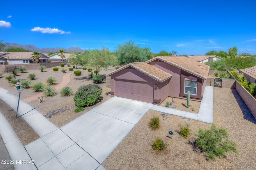 Absolutely immaculate, pristinely upgraded west side home on premium lot situated next to expansive common border and no neighbors behind! Tons of stylish updates include: beautiful wrought iron front door, modern kitchen w/ dark cabinetry & SS pulls, quartz counters, electric glass cooktop, oversized sink, updated light fixtures & smart lighting, hard flooring throughout,  hall bathroom has decorative floor to ceiling backsplash & glass shower enclosures, dual-tone paint, solar tubes, master bath has dual vanity, large garden tub & walk-in closet,  laundry room has been remodeled with pullout ironing board, stackable W/D convey, and tons of cabinets, French doors open to the large private backyard that is beautifully landscaped with pavers, fireplace, decorative gravel and has a large grassy area that is perfect for pets! System upgrades include new AC April 2022, water lines replaced from the main line to the house in 2016, Tankless water heater installed in 2016! Conveniently located near I-10, Tumamoc Hill, A Mountain, St Mary's Hospital, grocery stores, Pima Community College with easy access to downtown, U of A & more!