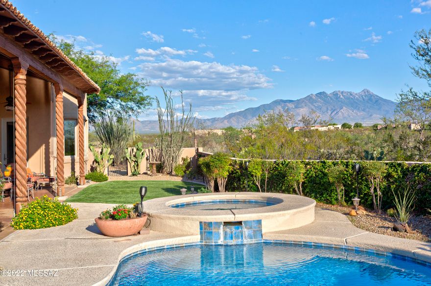 Panoramic mountain and city views with privacy nestled on .74 acres in Madera Reserve. Situated on a cul de sac, a private driveway leads you to this captivating home. A soothing waterfall in the spacious front courtyard welcomes you. Enter to find Saltillo tile leading to a great room with beehive fireplace and walls of windows to enjoy the views. Spectacular kitchen with granite countertops, island, SS appliances, abundant storage, and nook with slider. Entertain in the elegant dining room with artistic ceiling. Luxury main suite w/ bay window. access to the rear patio, bathroom with separate vanities, soaking tub, walk in shower, and large walk-in closet. Second suite provides privacy with ensuite bathroom. A den overlooking the front courtyard bringing tranquility. Step out back to find a covered wrap around patio overlooking the solar heated pool and spa with Santa Rita Mountains as the backdrop. Plenty of storage in the extended 3 car garage with cabinets, sink, and epoxy flooring. True tranquility awaits!
